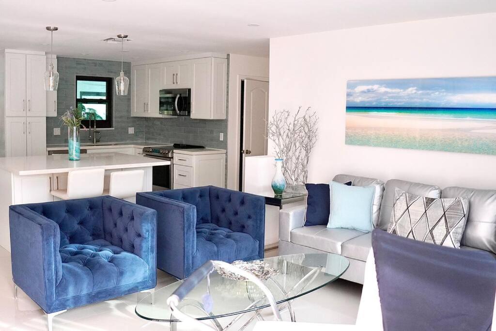 cocina con 2 sillas azules y mesa de cristal en Stylish home, en Dania Beach