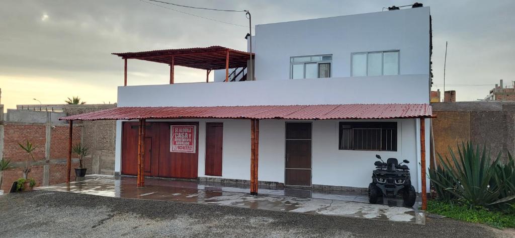 un pequeño edificio blanco con techo rojo en Casa de playa, en Asia