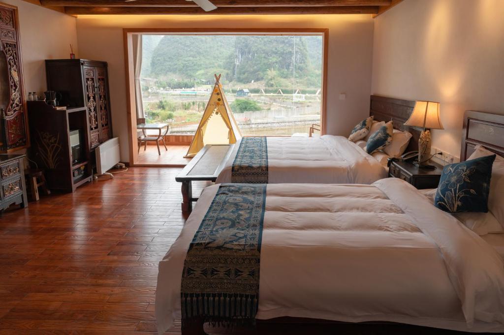 a bedroom with two beds and a large window at Yangshuo Tea Cozy in Yangshuo