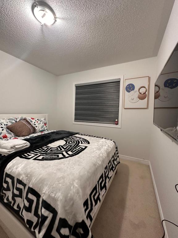 a bedroom with a bed with a black and white comforter at Bellhaven Beautiful Home in Brampton