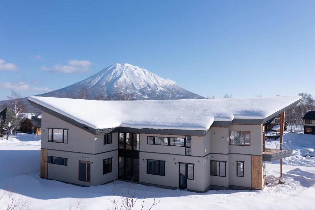 a house with a snow covered mountain in the background at Ro-An in Niseko