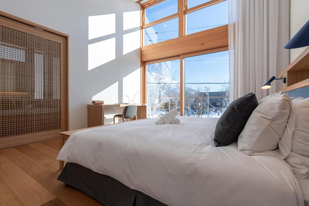 a bedroom with a large white bed with a large window at Ro-An 炉庵 in Kutchan