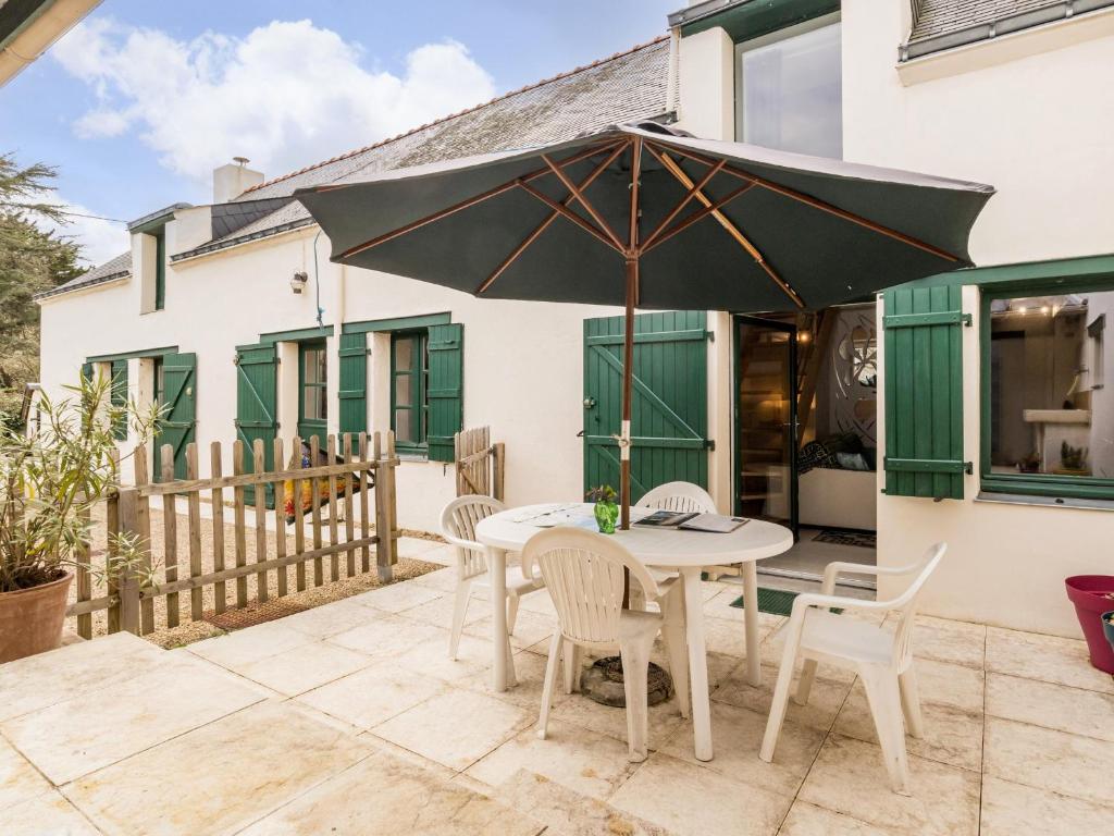 a patio with a table and chairs and an umbrella at Gîte breton proche plages et Guérande - terrasse, vélos inclus, animaux bienvenus - FR-1-306-1268 in Assérac