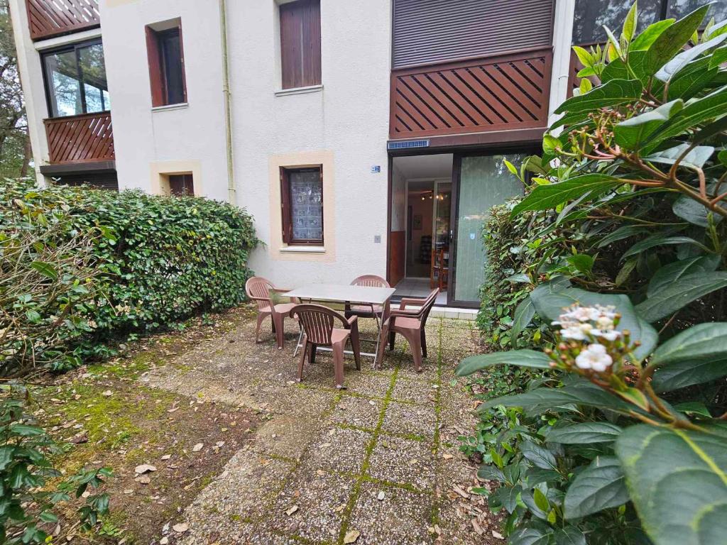 un patio avec une table et des chaises devant un bâtiment dans l'établissement Appartement T2 en Rez-de-Jardin, Terrasse, à 300m de la Plage, Parking, Environnement Calme et Boisé - FR-1-550-71, à Saint-Georges-de-Didonne