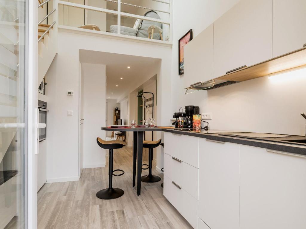 une cuisine avec des armoires blanches et un comptoir dans l'établissement Charmant gîte indépendant avec terrasse, proche plage et golf, idéal pour des vacances à Pornic - FR-1-306-1267, à Pornic