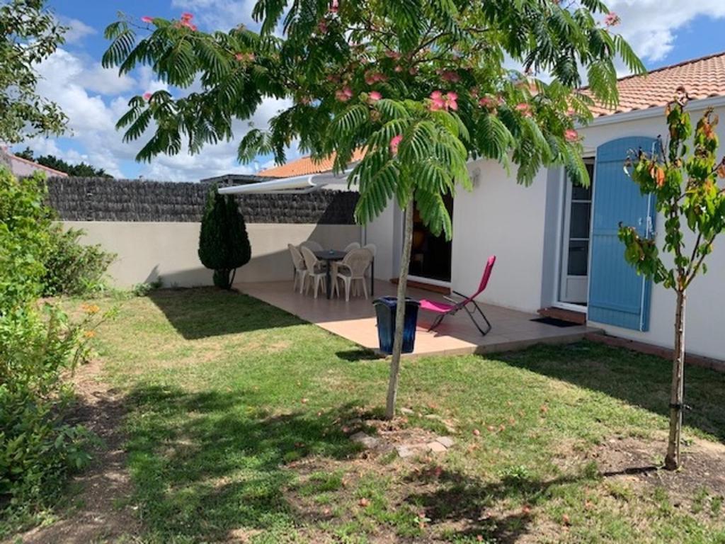 une maison avec un palmier dans la cour dans l'établissement Maison 3 chambres au calme, 3* - Proche plage et commerces, WiFi, terrasse, jardin, TV box, garage - FR-1-323-525, à Saint-Jean-de-Monts