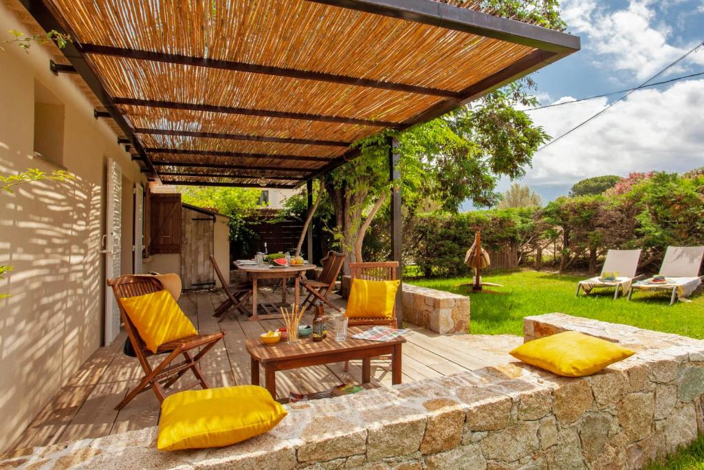 une terrasse avec une pergola en bois, une table et des chaises dans l'établissement Very warm villa "Acacia" with beautiful garden - 46 people, à Calvi