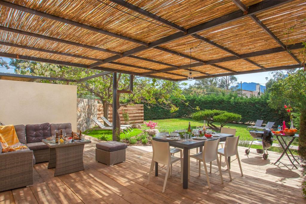 un patio al aire libre con pérgola de madera en Villa Albizzia with terrace and garden 6 8 people en Calvi