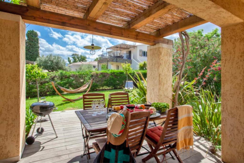 a patio with a table and chairs and a grill at Maisonnette une chambre "Yucca" 2 à 4 personnes in Calvi
