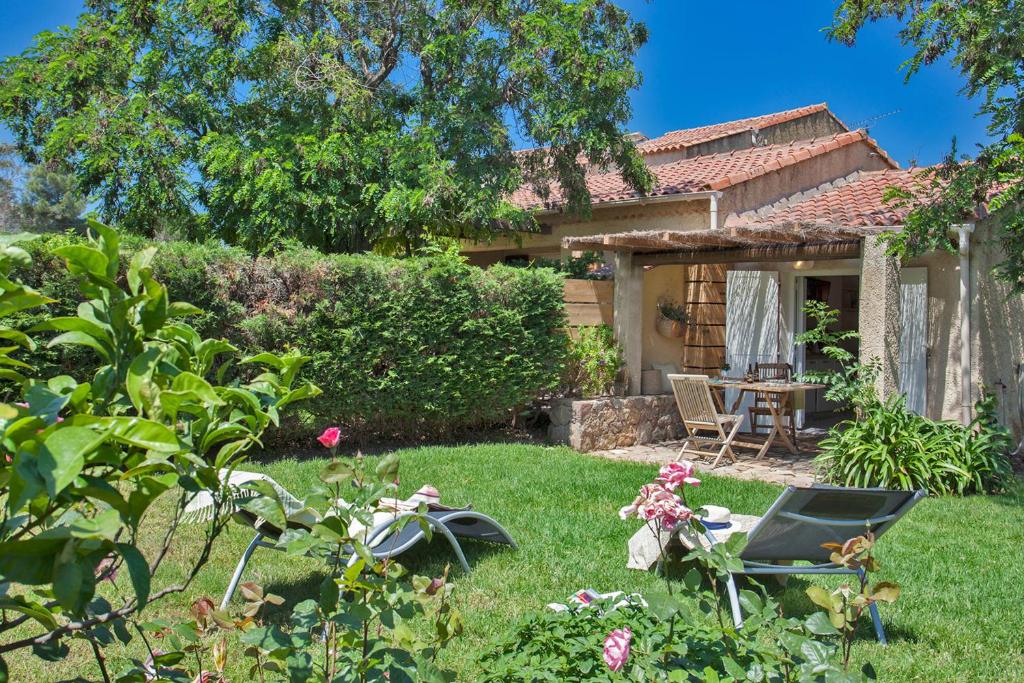 a garden with a table and chairs in front of a house at Quiet mini-villa "Dracena" with its pretty garden - 2 people in Calvi