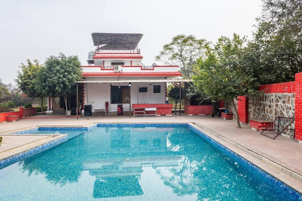 a swimming pool in front of a house at Aravali hills resort in Gurgaon