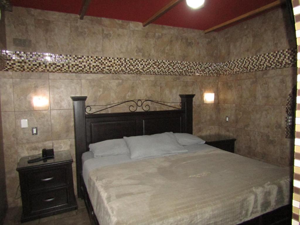 1 dormitorio con 1 cama grande y mesita de noche en Ruma San Luis Hotel Boutique, en San Luis Potosí
