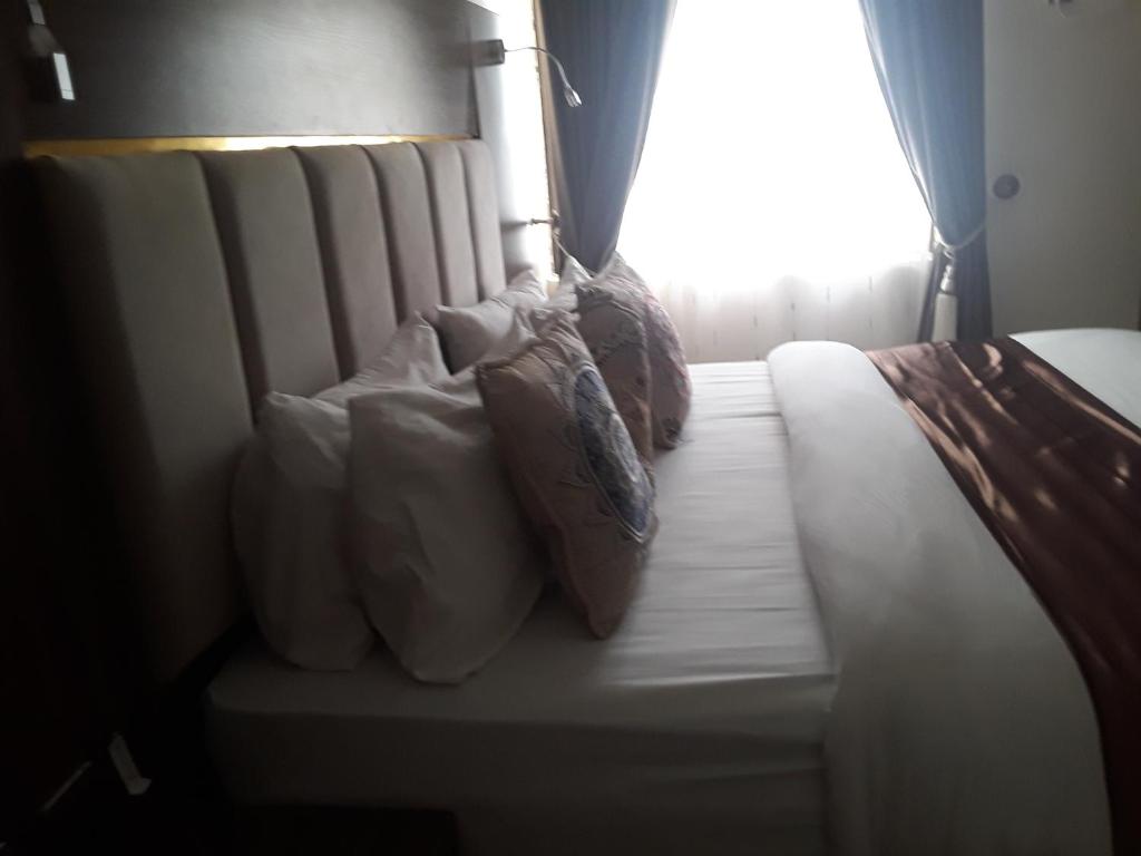 a bed with pillows on it with a window at Franzy Luxury Hotel & Suites in Jos