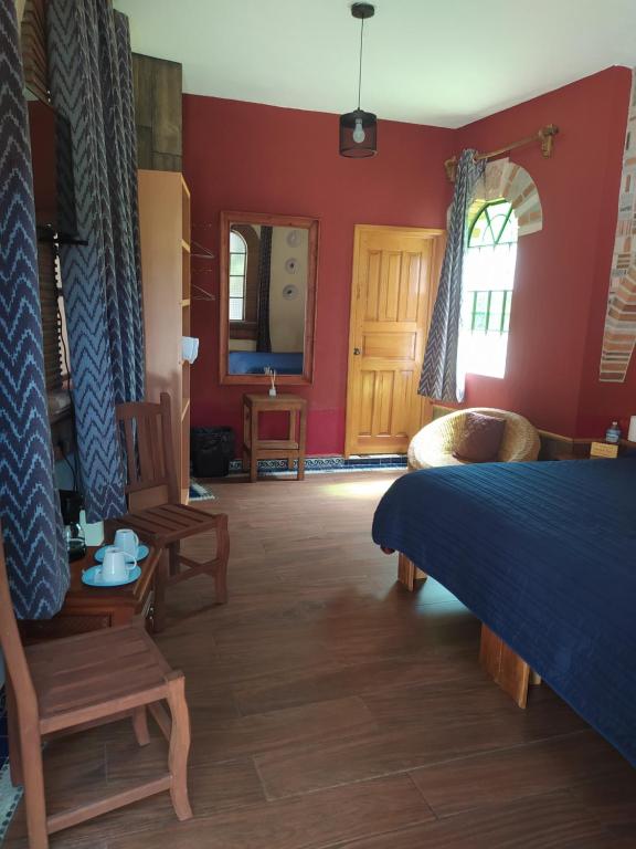 a bedroom with a blue bed and red walls at Hotel Villas San Miguel in Pátzcuaro