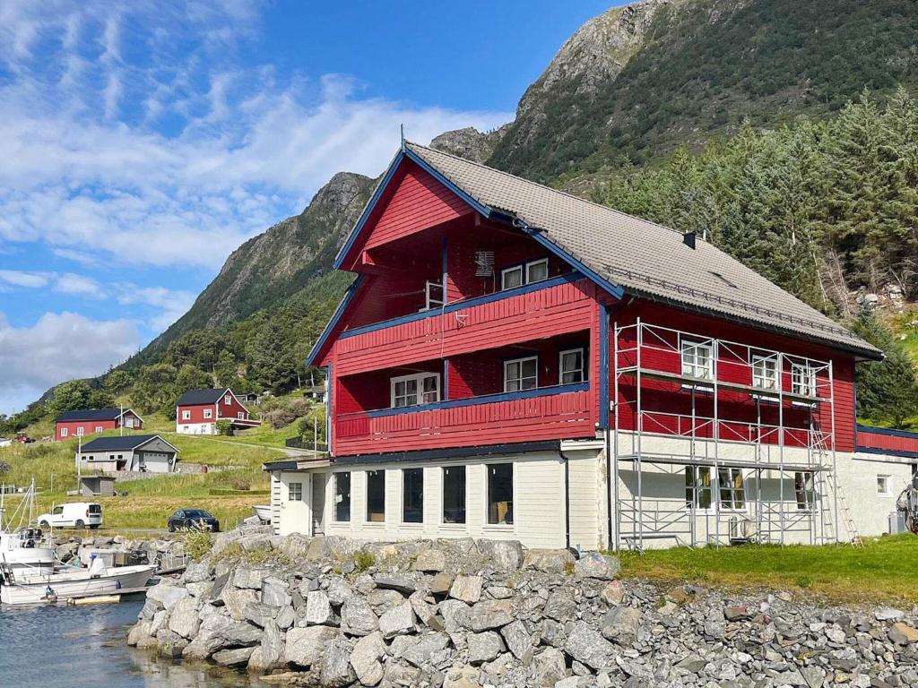 a red and white building next to a mountain at 4 person holiday home in Selje in Selje