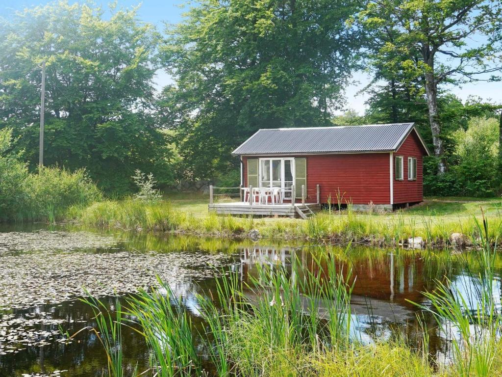 4 person holiday home in SMEDSTORP في Smedstorp: كابينة حمراء بجانب جسم ماء