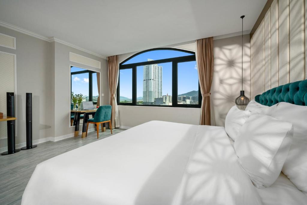 a bedroom with a white bed and a large window at Lupin Center Da Nang Hotel in Danang