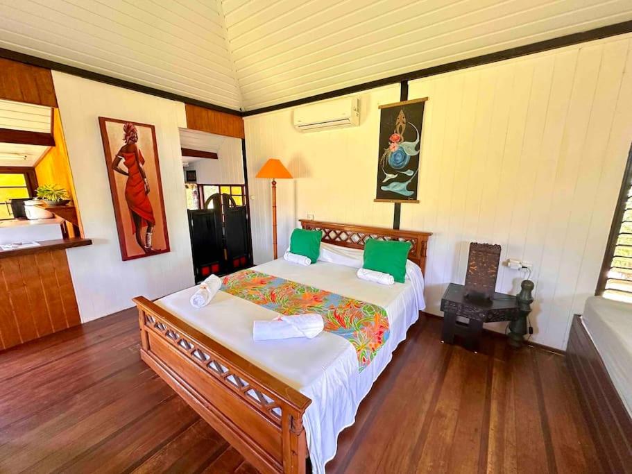 um quarto com uma cama grande e almofadas verdes em Fare Mahana - plage priveé avec vue sur Tahiti em Maatea