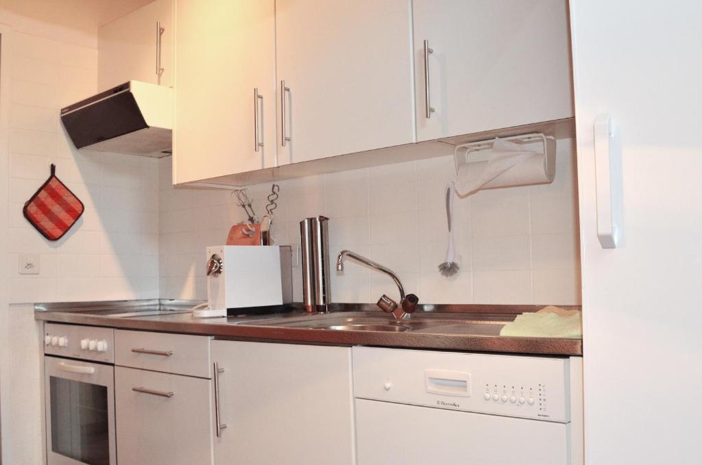 a kitchen with white cabinets and a sink at Chalet Memory in Zermatt