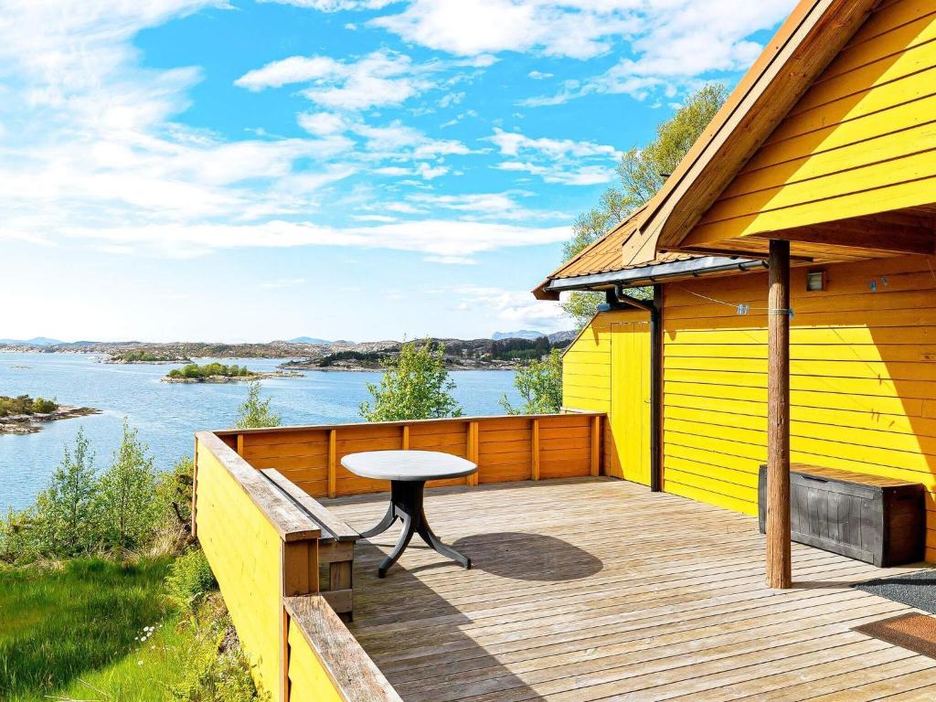 uma casa amarela com uma mesa num deque de madeira em 6 person holiday home in nneland em Ånneland