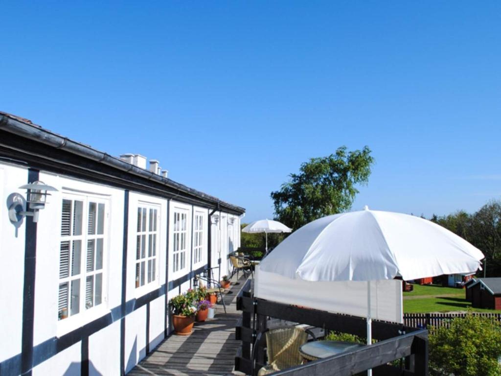 a white building with an umbrella on a patio at 4 person holiday home in Svaneke in Svaneke