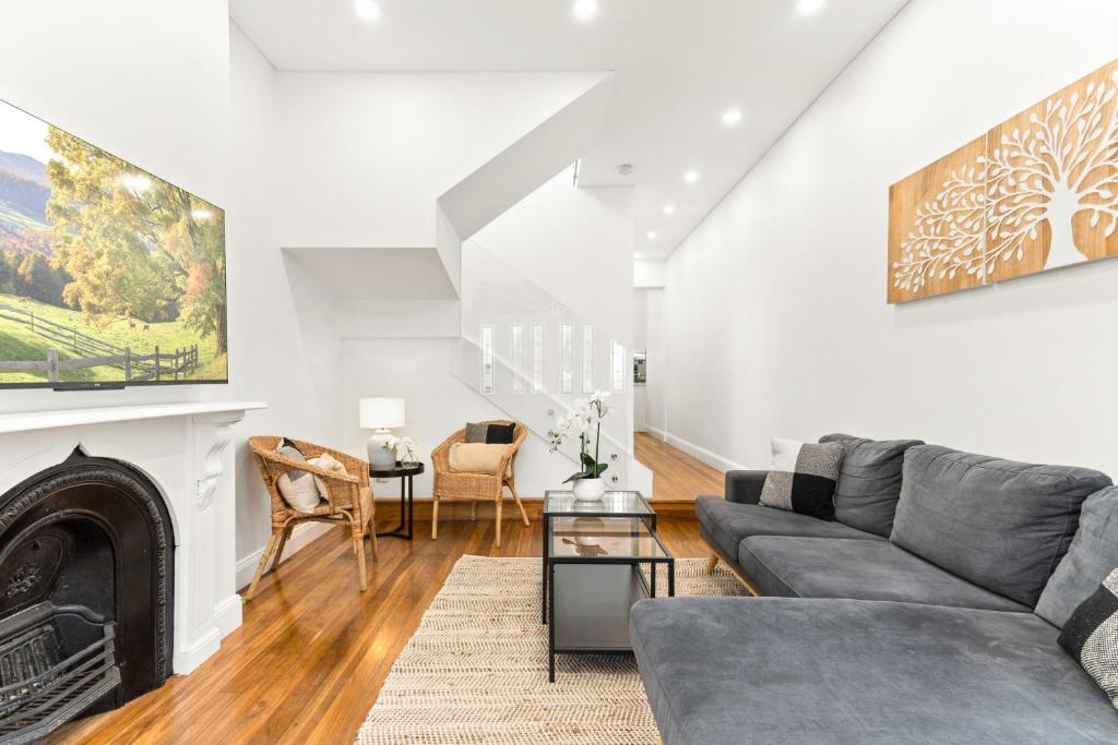 un soggiorno con divano e camino di Chic 3-Bed House with a Cosy Courtyard a Sydney