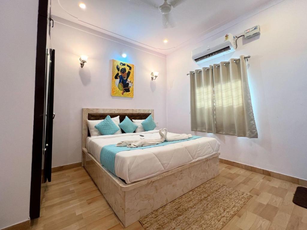ein Schlafzimmer mit einem Bett mit blauen Kissen und einem Fenster in der Unterkunft The heavens villa udaipur in Udaipur