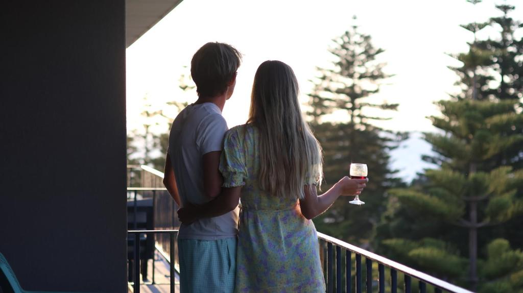 a couple standing on a balcony with a glass of wine at Cottesloe Sea Bliss Apartment in Perth