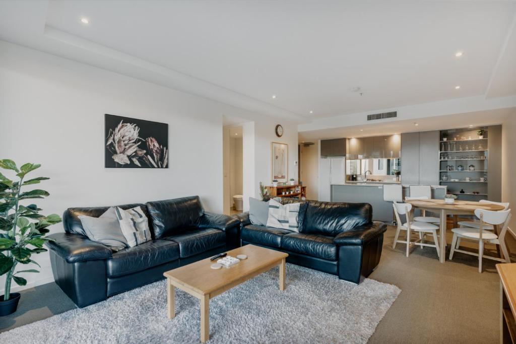 a living room with two leather couches and a table at Central Located 2-Bed with Pool, Gym & Parking in Canberra
