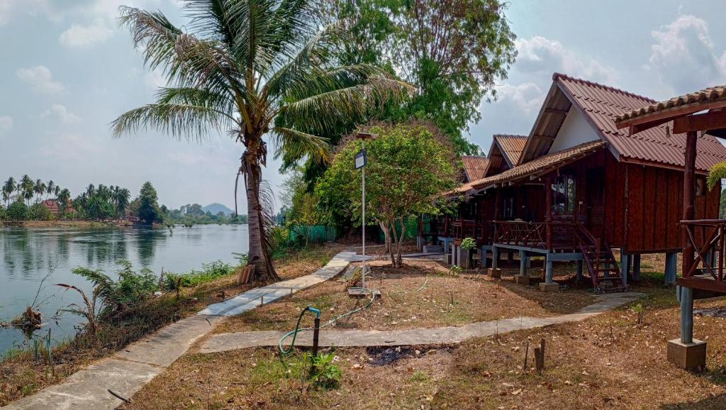a house by the water with a palm tree at Bon Tai Oasis Bungalows in Muang Không