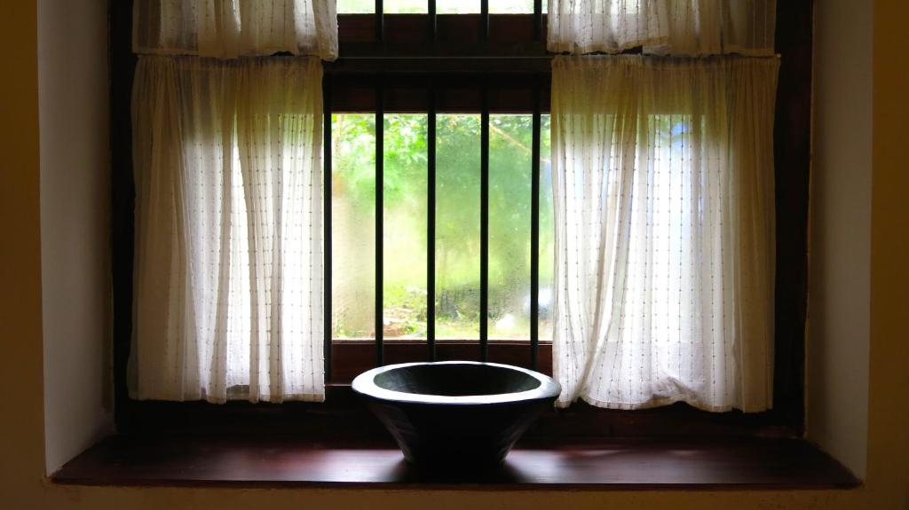 - une fenêtre avec un bol devant dans l'établissement Clayfingers Art Cottage, à Thrissur