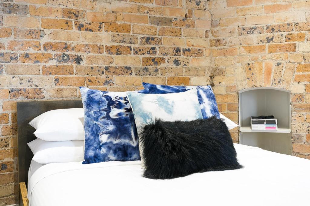 雪梨的住宿－Surfside Getaway in the Heart of Manly，一张带蓝色和白色枕头的床和砖墙