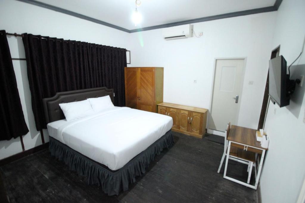 ein Schlafzimmer mit einem Bett, einem Stuhl und einem TV in der Unterkunft DE Homestay Banjarmasin in Benuaanyar