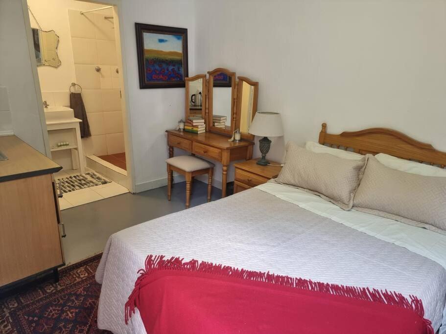 a bedroom with a large bed and a desk at Cottage by the Woods in Pretoria