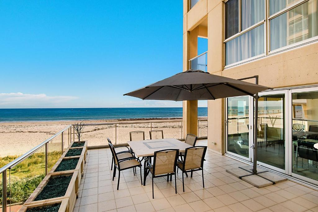 a patio with a table with chairs and an umbrella at Glenelg Beachfront Luxury Apartment in Glenelg