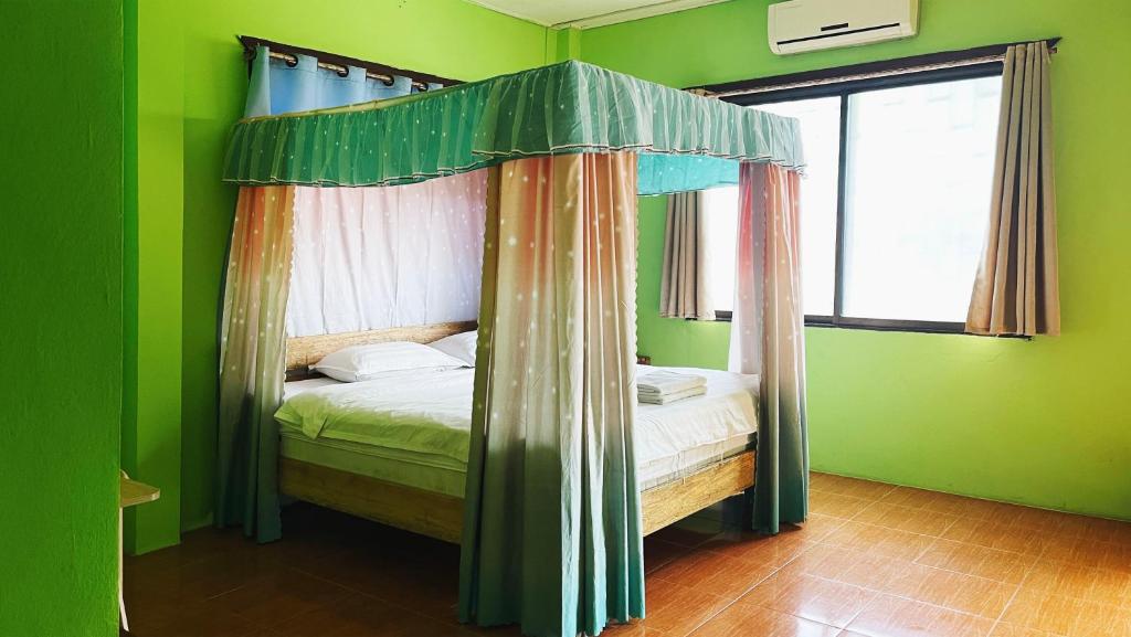 a bed with a canopy in a green bedroom at sokxay guerthouse in Vang Vieng