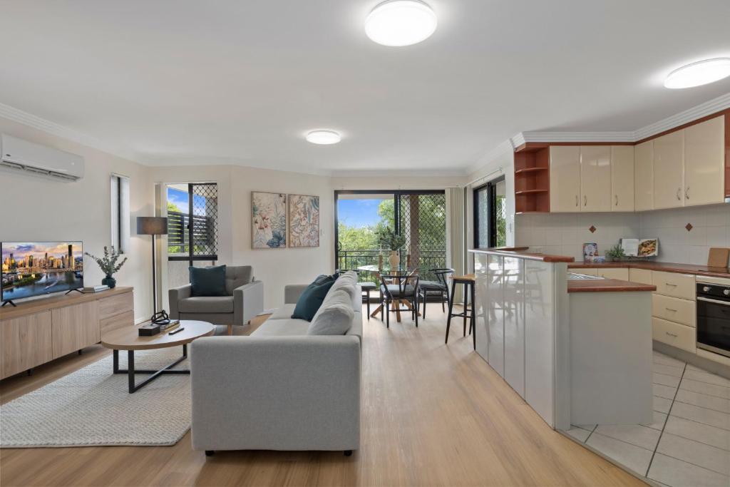 een keuken en een woonkamer met een bank en een tafel bij Comfy 2-Bedroom Family Apartment with Free Parking in Brisbane
