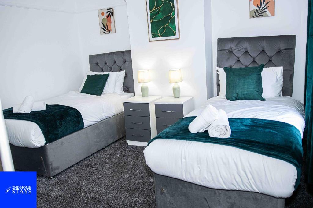 two beds in a room with green and white at 2ndHomeStays- Stoke-on-Trent-A Serene 3 Bed House with a Garden View-Suitable for Contractors-Relocation Families-Group of Friends-Sleeps 6 - 16 mins to J15 M6 and 36 mins to Alton Towers Resort in Stoke on Trent