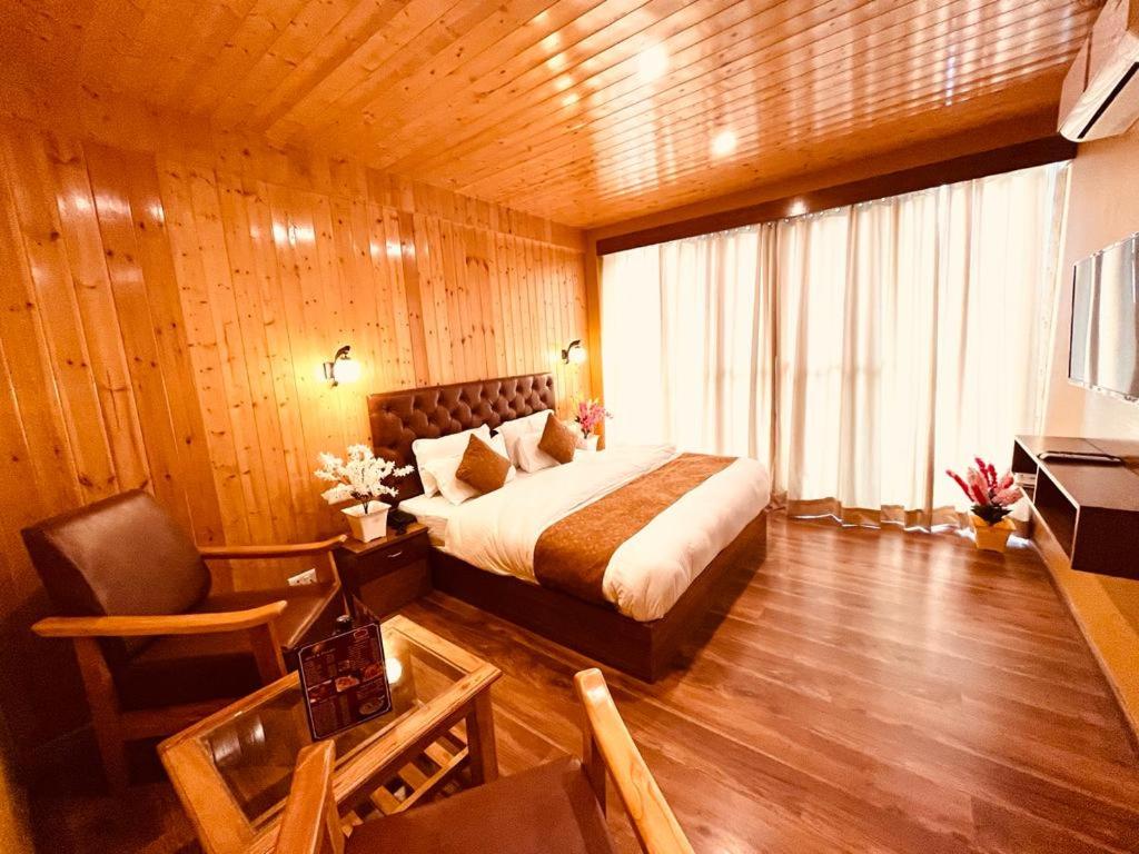 a bedroom with a bed and a chair in a room at Vista Resort - Managed BY The Four Season, Close to Manali Mall Road in Manāli