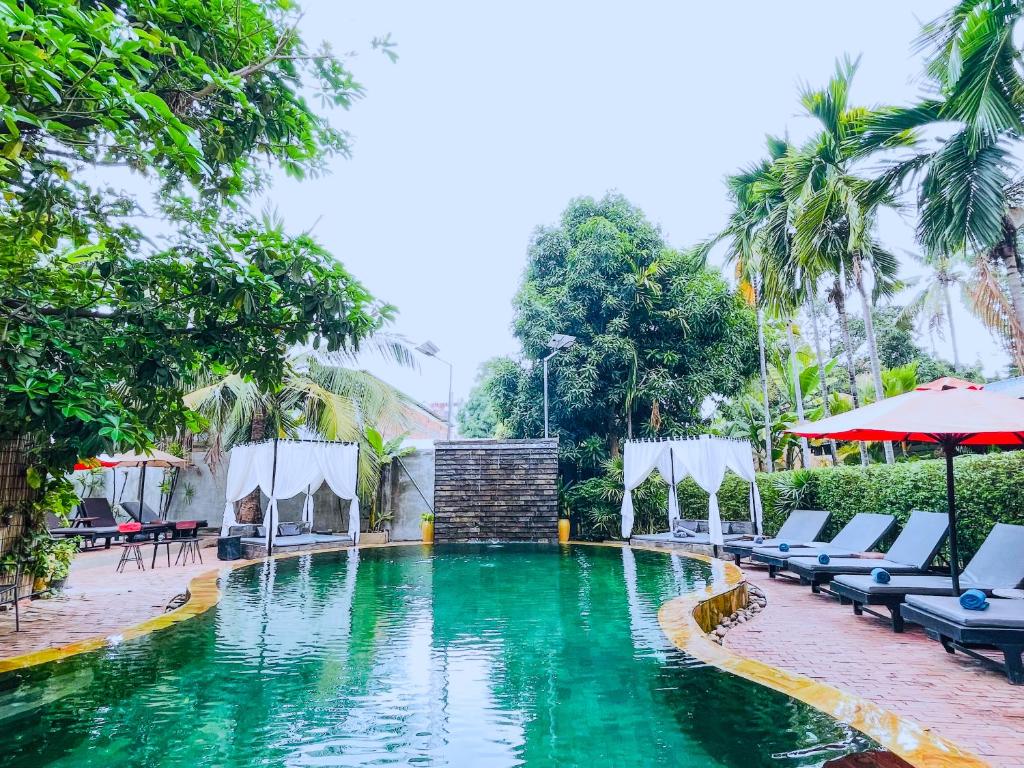 a pool at a resort with chairs and umbrellas at Central Privilege Hotel in Siem Reap