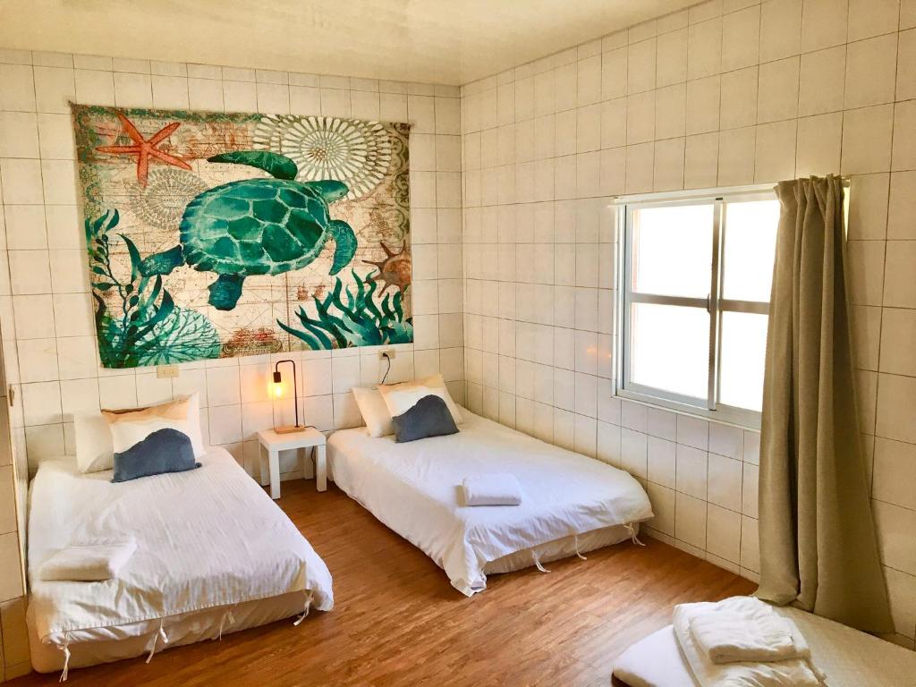 um quarto com duas camas e uma foto de uma tartaruga na parede em Liuqiu Cozy Room em Xiaoliuqiu