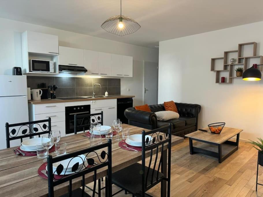 uma cozinha e uma sala de estar com mesa e cadeiras em Appartement Cosy em Louhans