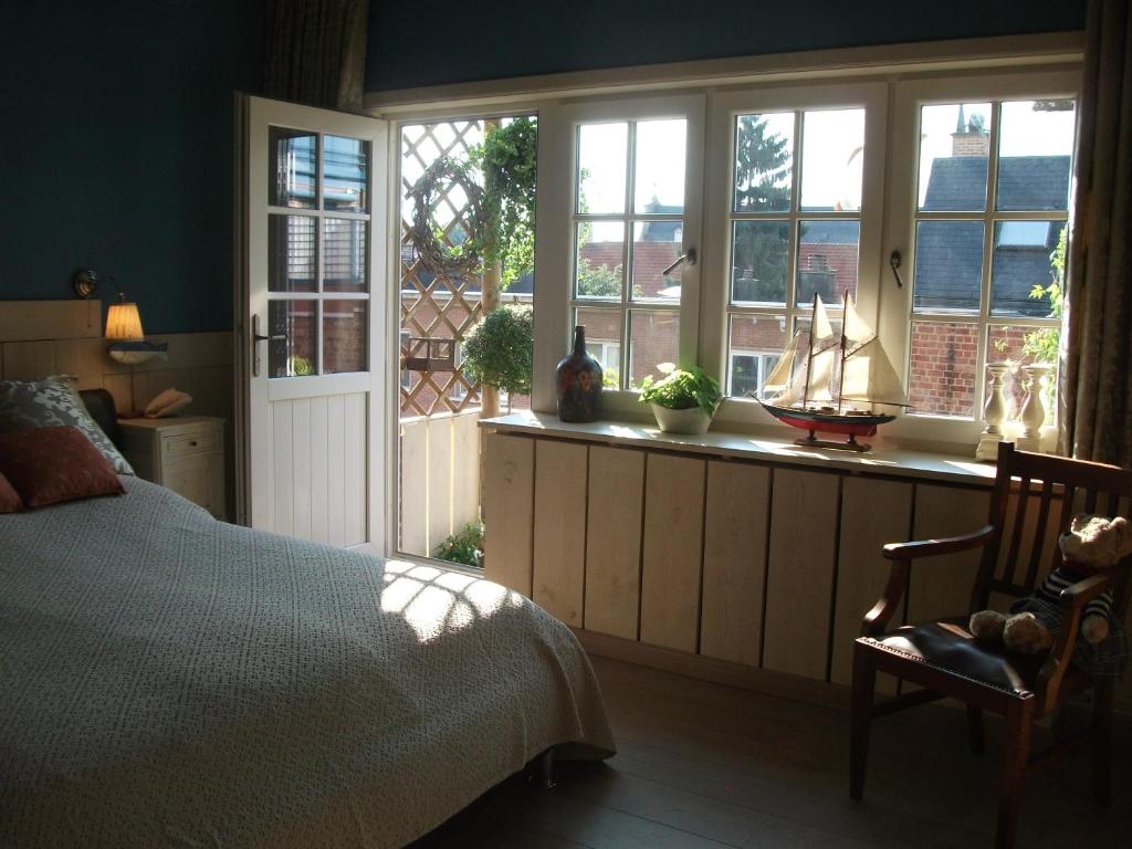 1 dormitorio con cama, ventanas y silla en Apartment Het Demerhuisje, en Hasselt