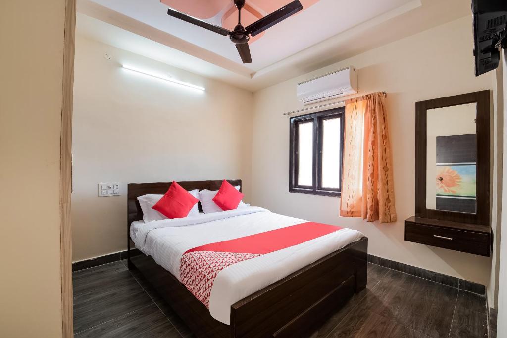 um quarto com uma cama com almofadas vermelhas e uma janela em OYO Seera Enclave em Rajahmundry