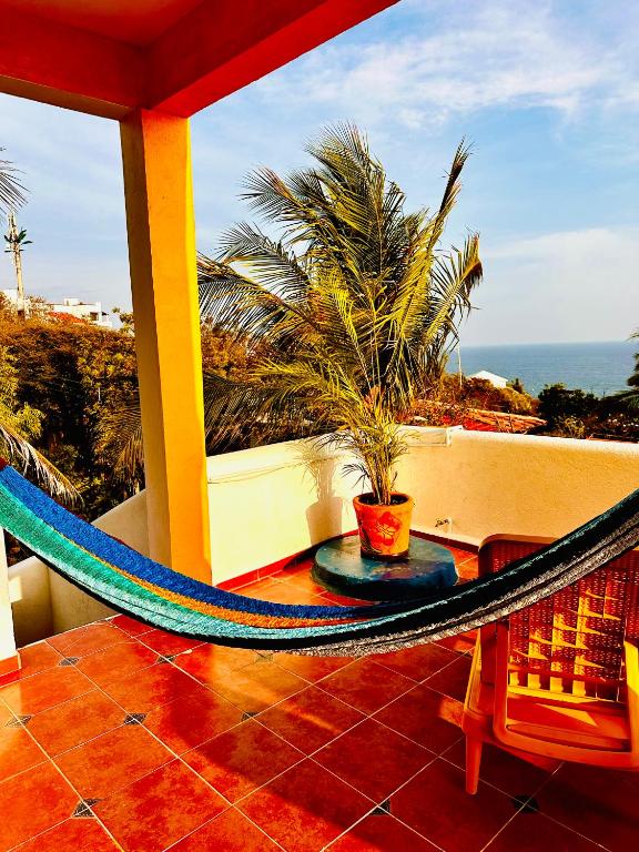 a hammock on a balcony with a view of the ocean at La Casa de Colores Ocean View in Puerto Ángel