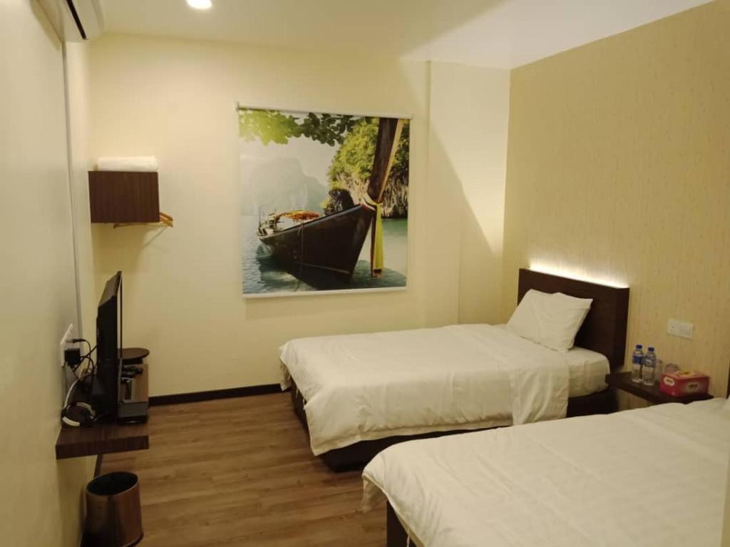 a room with two beds and a painting of a person in a boat at Z&H Homestay in Kuala Selangor