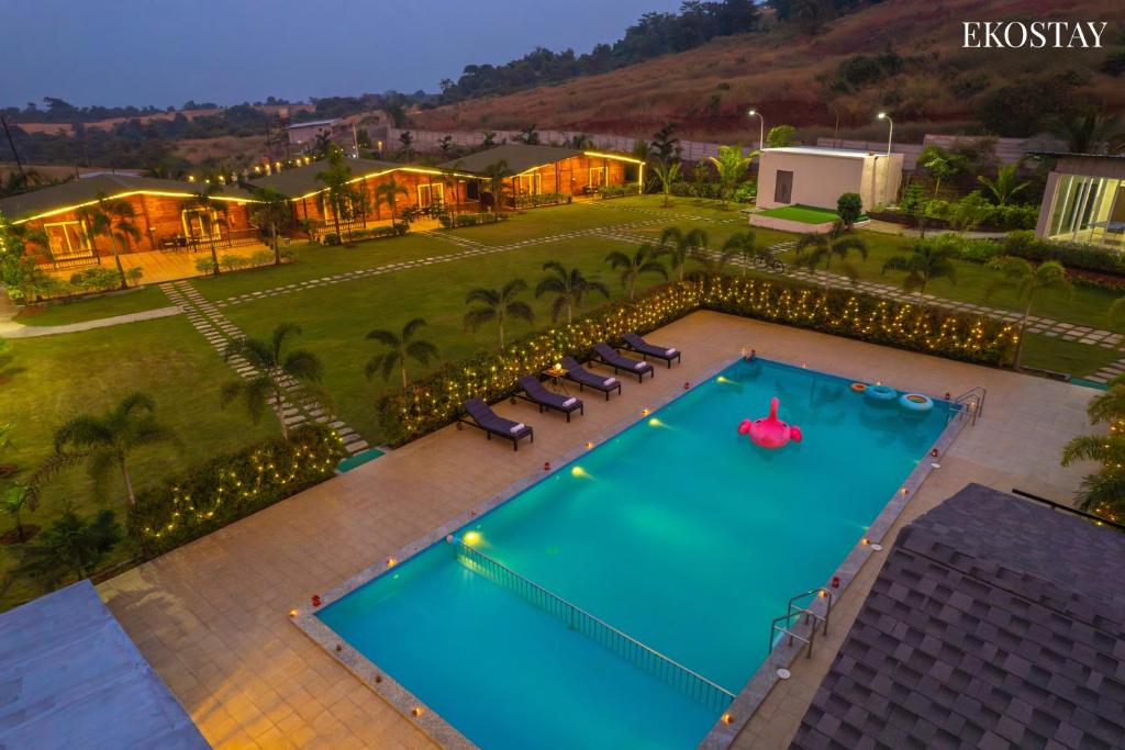 an overhead view of a swimming pool with loungers and a resort at EKOSTAY Luxe - Woodstock Villa I 2 Acre Property I Cricket Turf I Party Friendly in Karjat