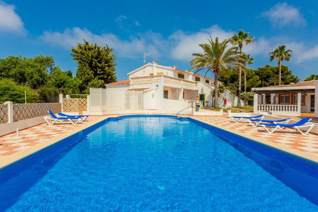 a swimming pool with chairs and a house at Apartamento en complejo de zonas ajardinadas-c11 in Ciutadella