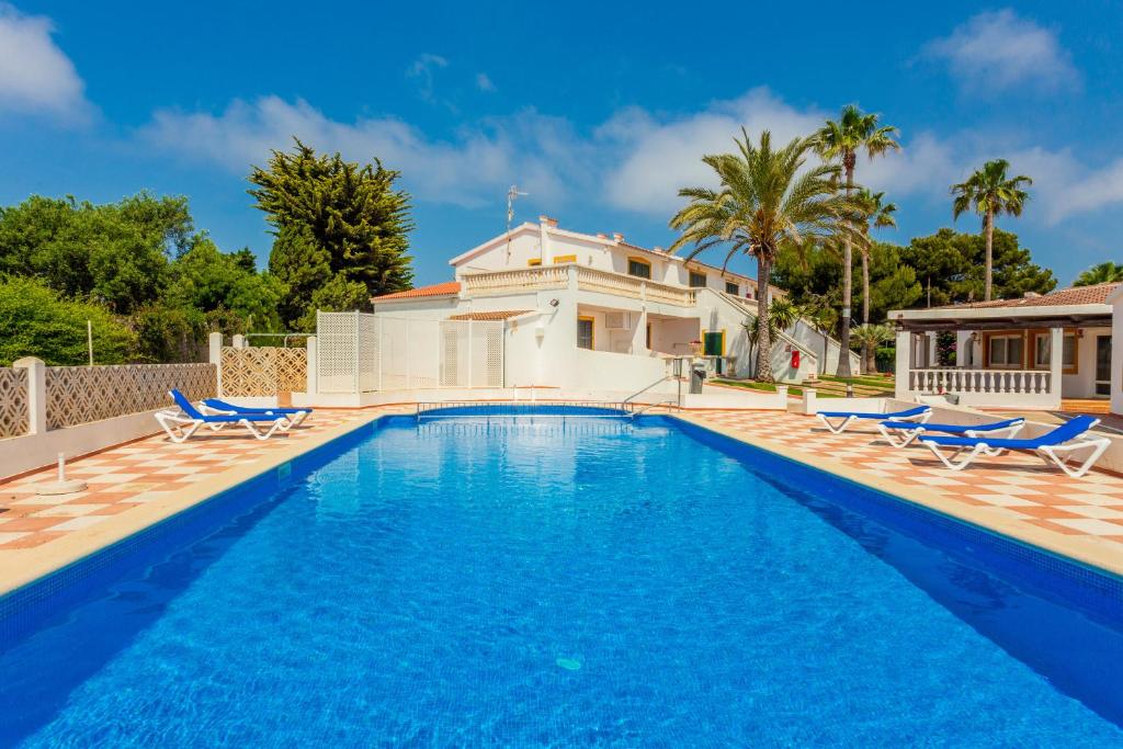 una piscina con sillas y una casa en Apartamento en complejo de zonas ajardinadas-c11, en Ciutadella