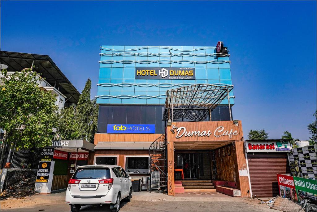 a car parked in front of a glass building at FabHotel Prime Dumas in Surat